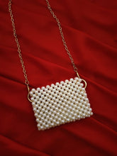 Detailed view of the long, shimmering golden strap attached to the beaded mini pouch