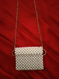 Elegant hand delicately grasping the mini beaded pouch, highlighting its compact size and luxurious feel