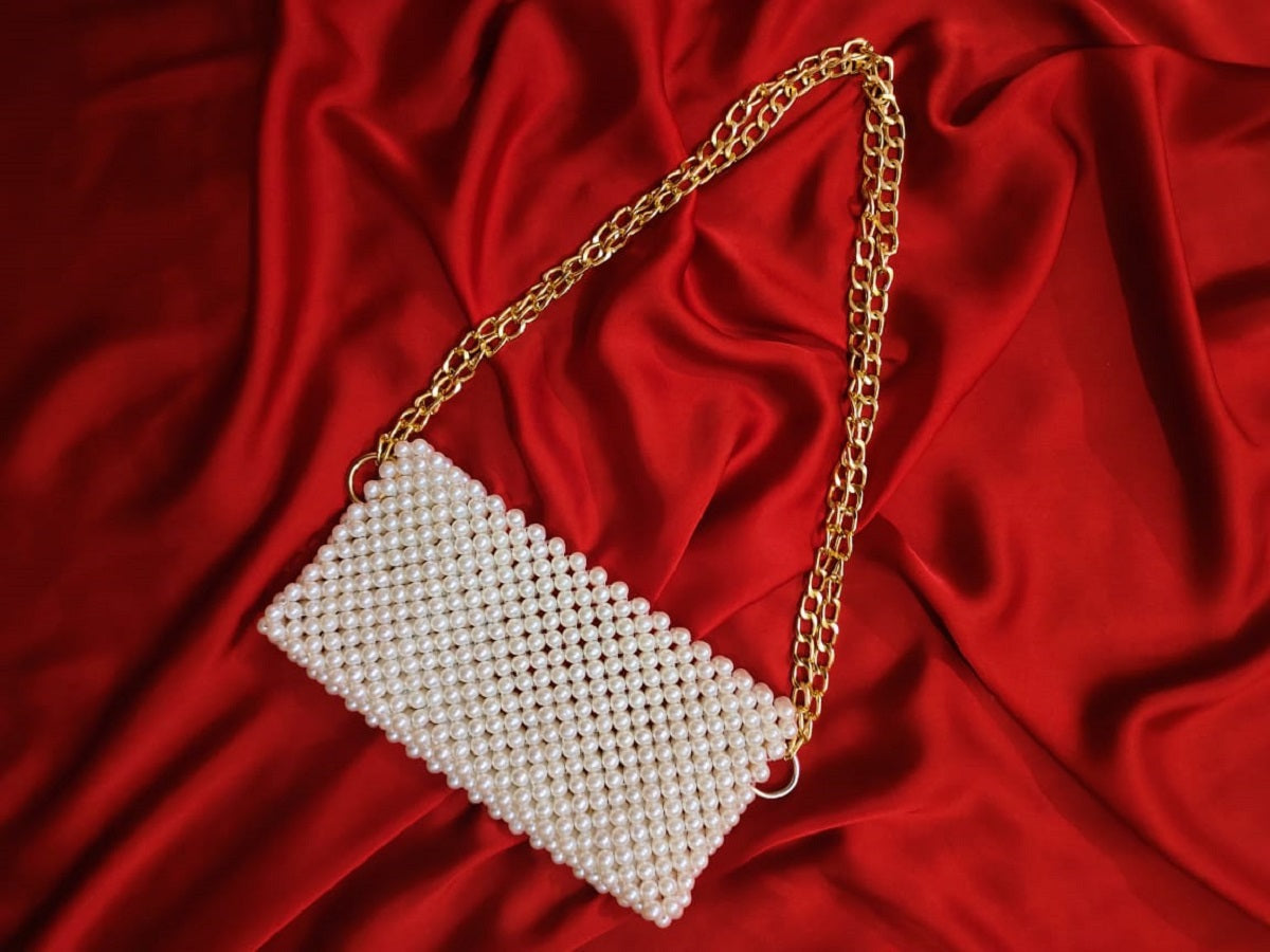 Lustrous golden strap of the beaded shoulder bag, reflecting elegance and luxury